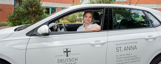 Junge Frau blickt aus dem Auto des Quartierszentrum St. Anna in die Kamera